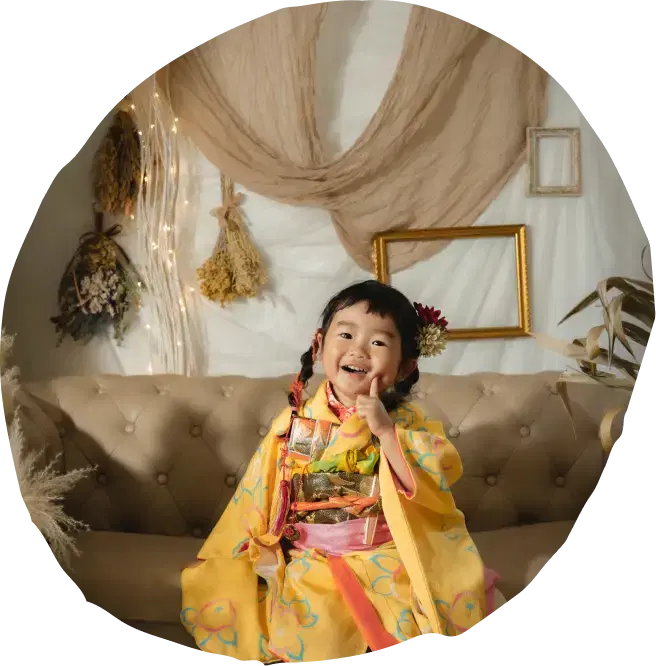 さまざまな小物がある室内で和装をした女の子がソファに座っている
